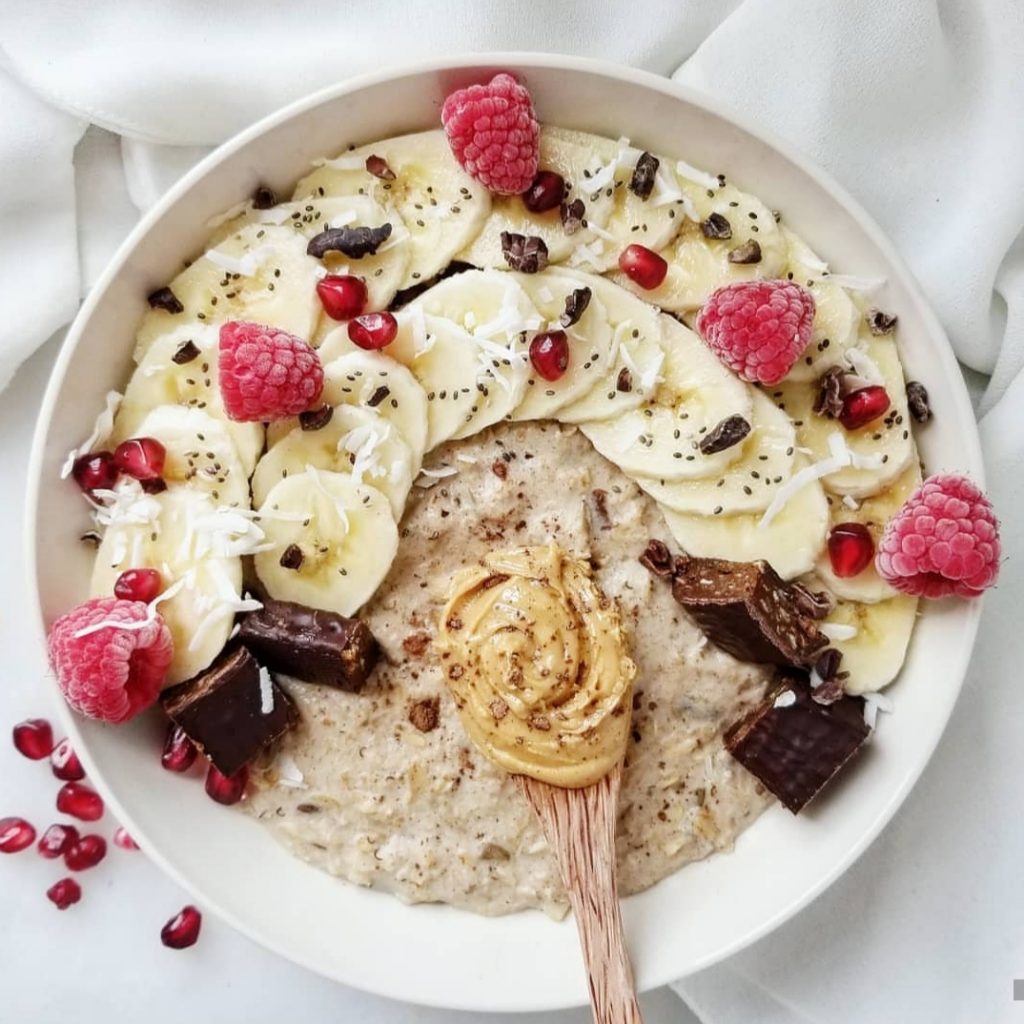 oatmeal topped with bananas, chia seeds, coconut flakes, and raspberries 