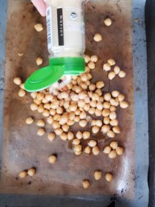 adding garlic to the chickpeas on a baking sheet