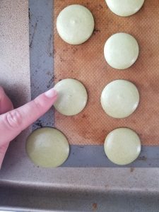 drying the piped matcha macarons on a baking tray before baking them 