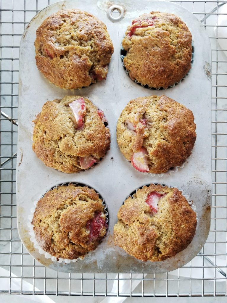 dairy free strawberry banana muffins with coconut oil in a muffin pan on a cooling rack
