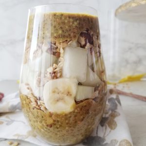 golden chia pudding in a tall stemless wine glass layered with melon and bananas 