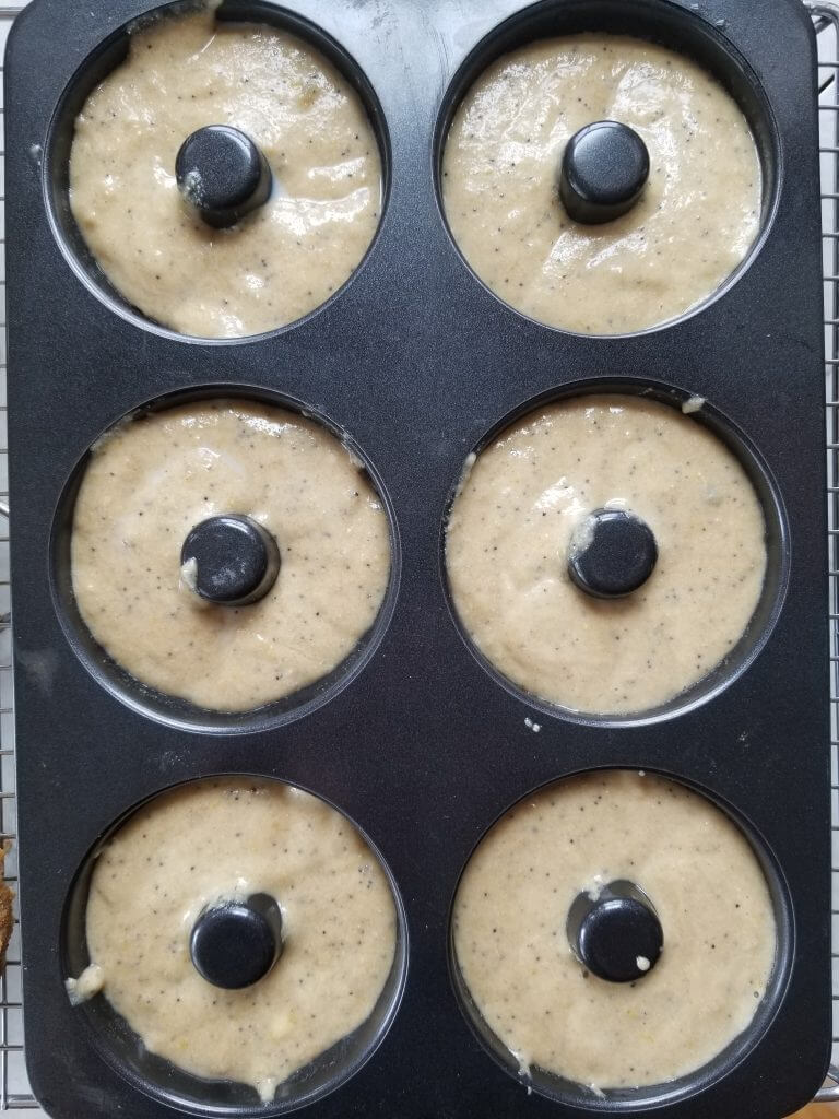 lemon poppy seed doughnuts in a doughnut pan before baking