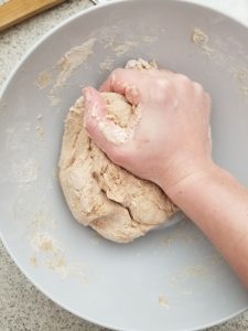 Using my hand to knead the whole wheat naan dough in a bowl 
