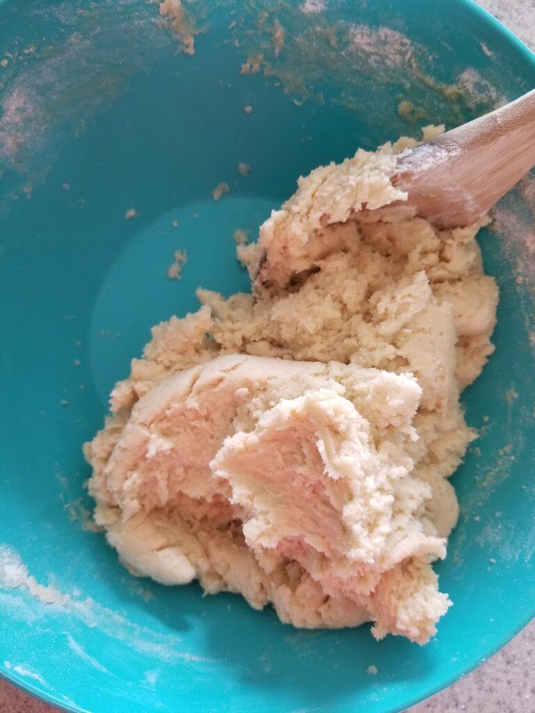 bowl of sugar cookie dough mixed with a wooden spoon