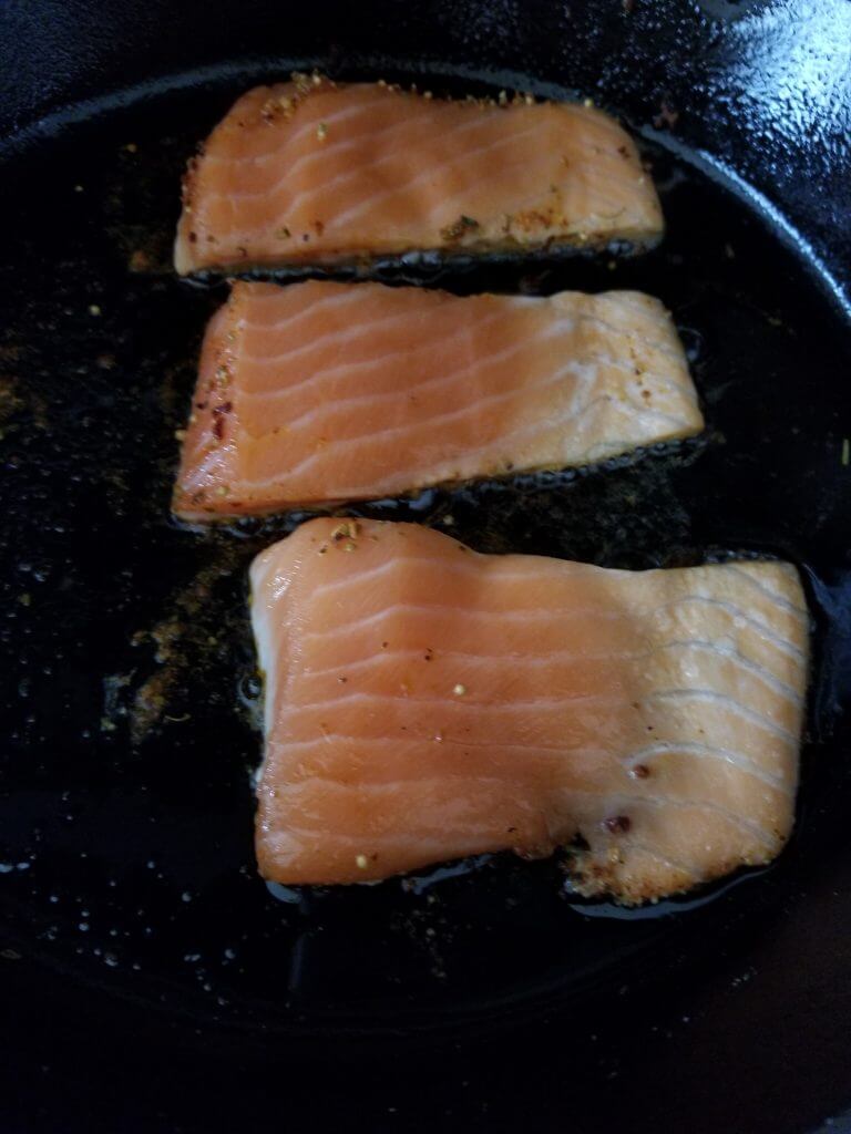 Arabic salmon cooking in a cast iron skillet