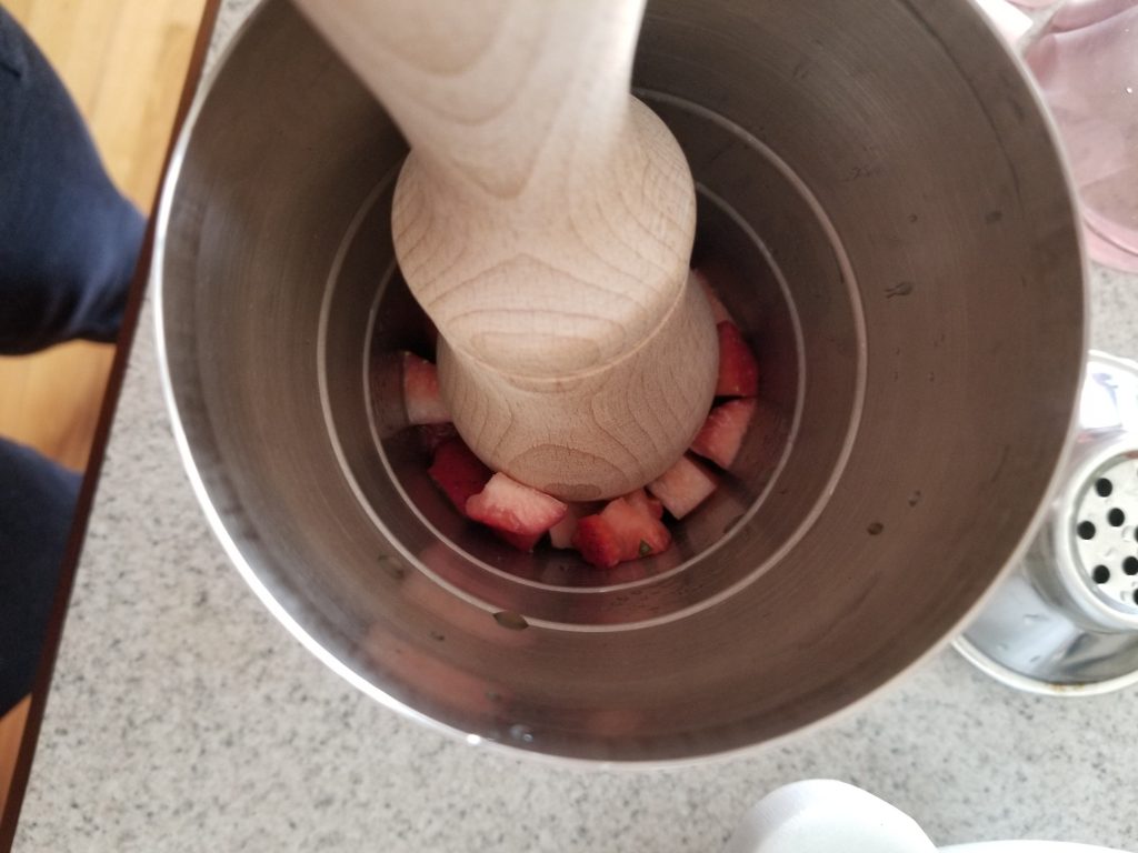 mashing the strawberries and basil with a pestle 
