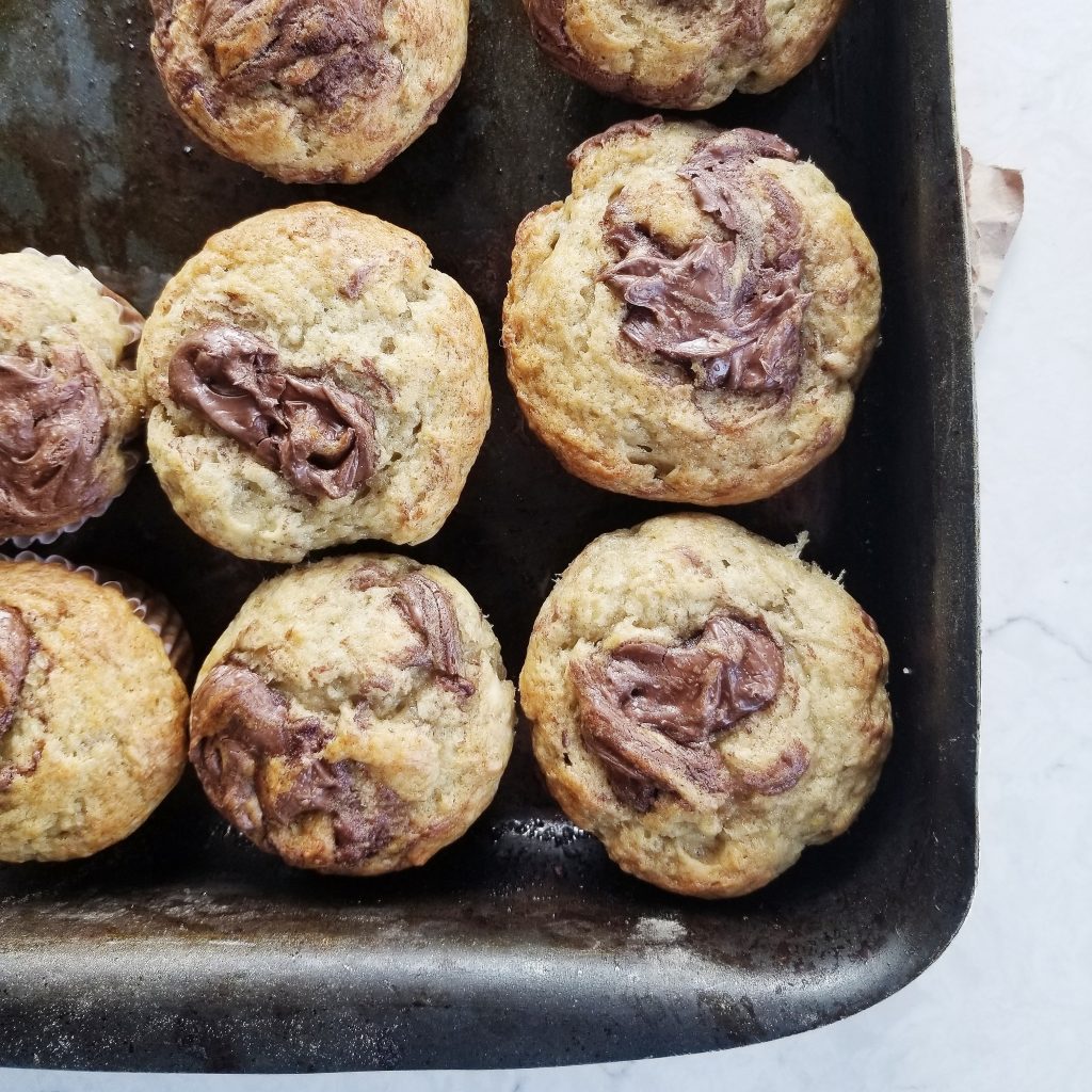 Baked dairy free nutella swirl banana muffins in a rustic baking pan