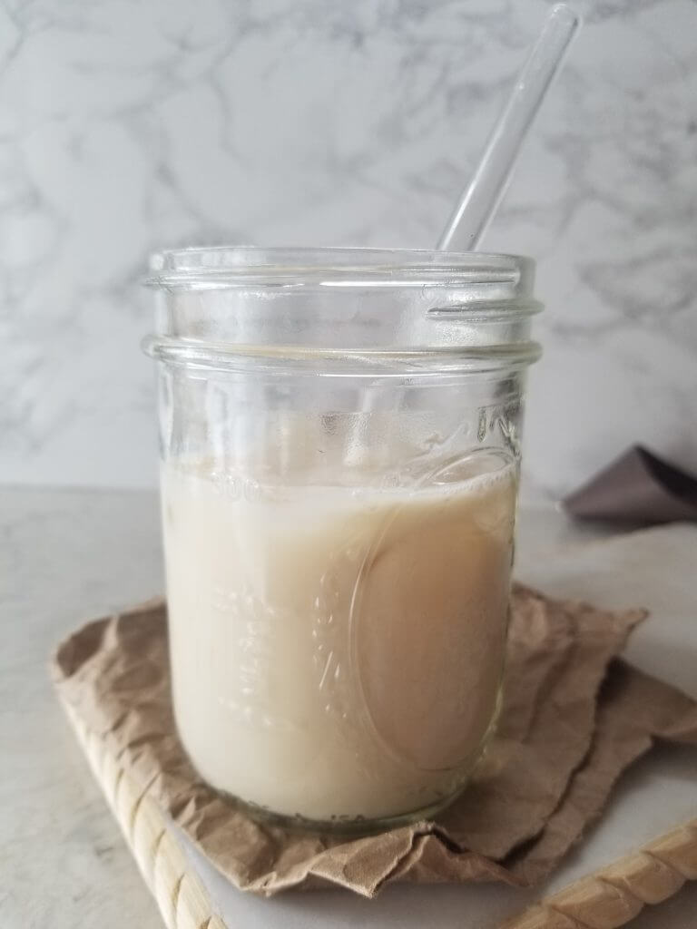 mason jar with milk and ice cubes and a glass straw