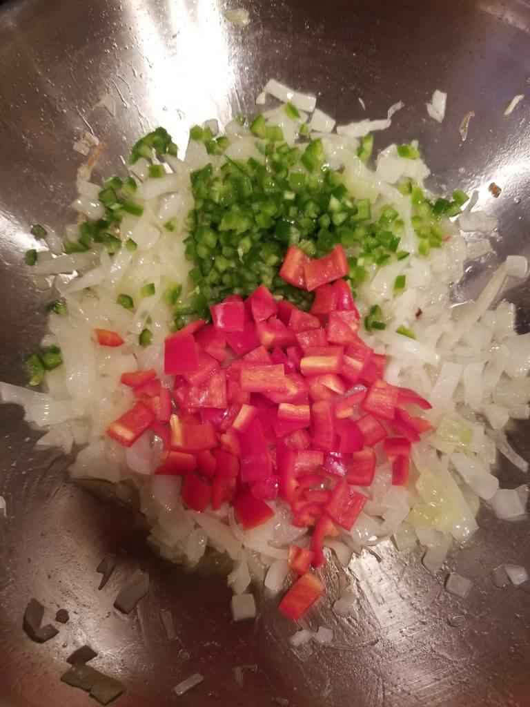 peppers and jalapenos added to the onions in the wok