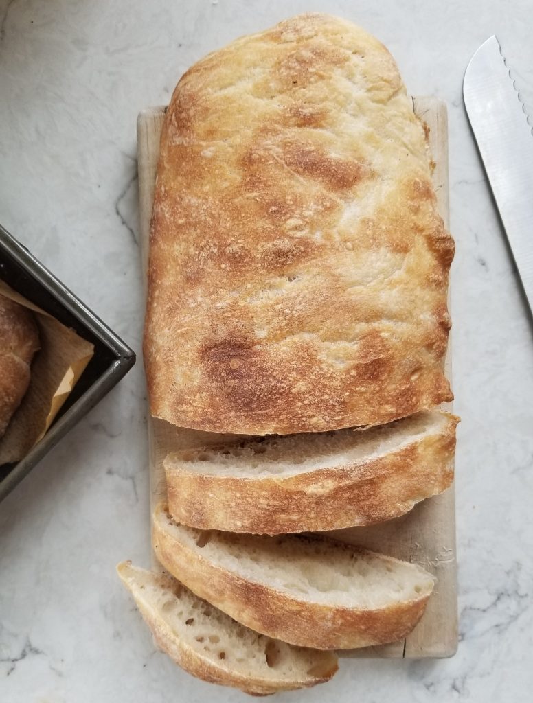 homemade ciabatta bread sliced on a cutting board