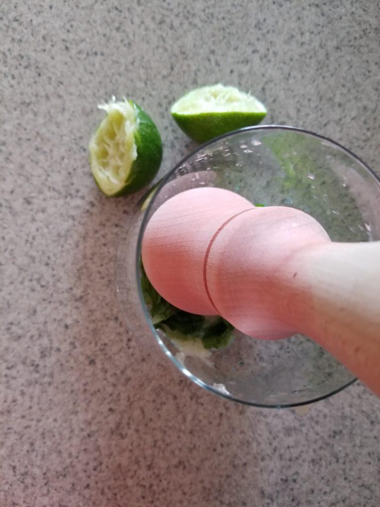 crushing mojito mint leaves in a glass with a pestle