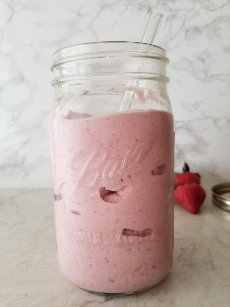 healthy strawberry banana smoothie in a mason jar with a glass straw 