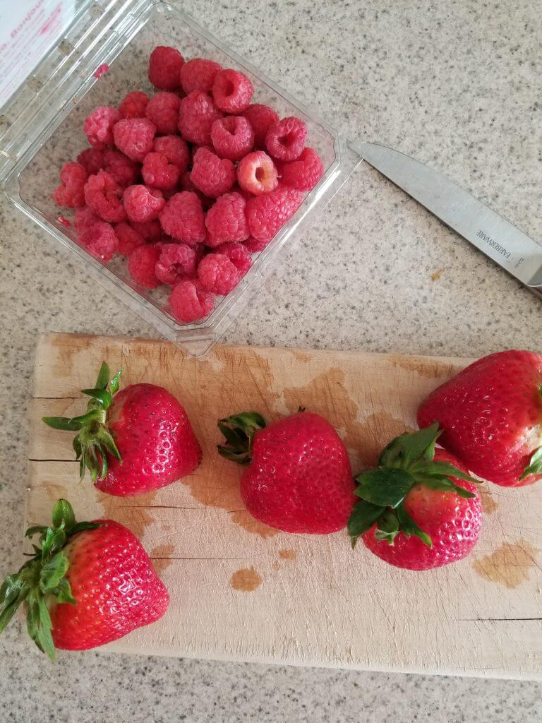 strawberries and raspberries on a cutting board