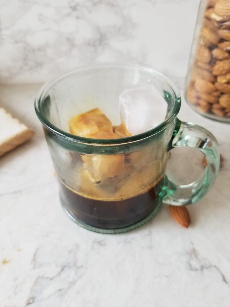 espresso over ice in a glass with almonds in the background