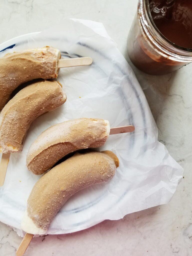 frozen peanut butter dipped bananas on a plate
