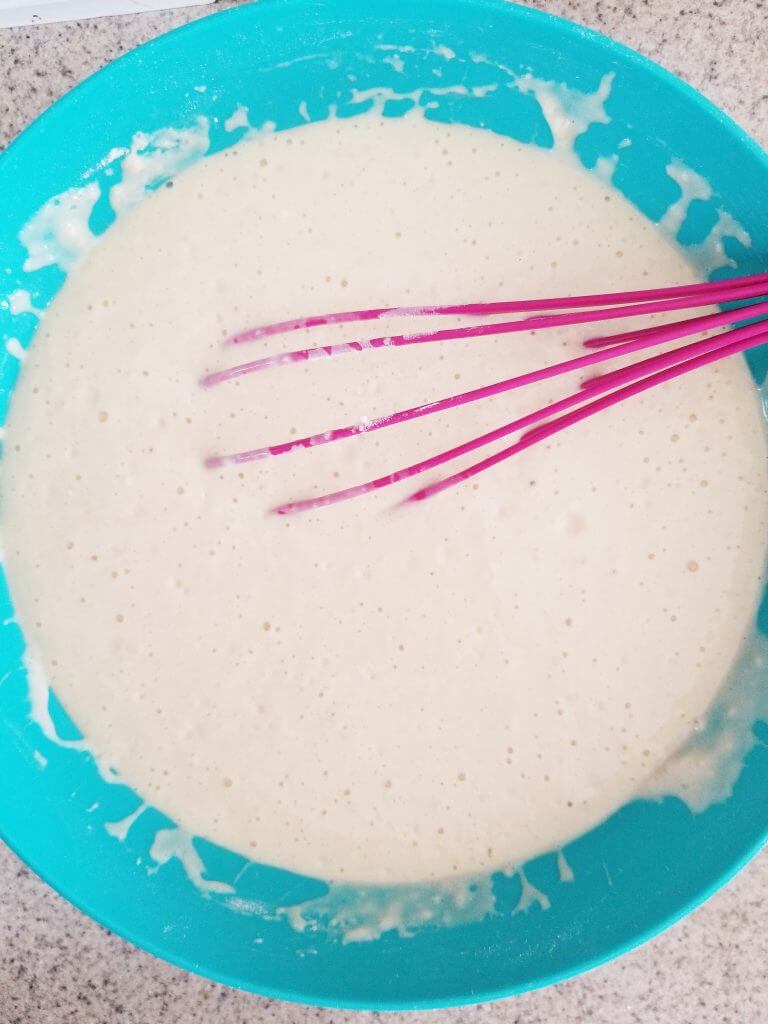 pancake batter with bubbles in a blue mixing bowl